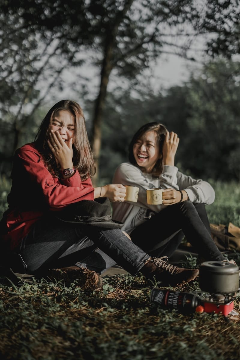 two friends holding cups laughing at each other