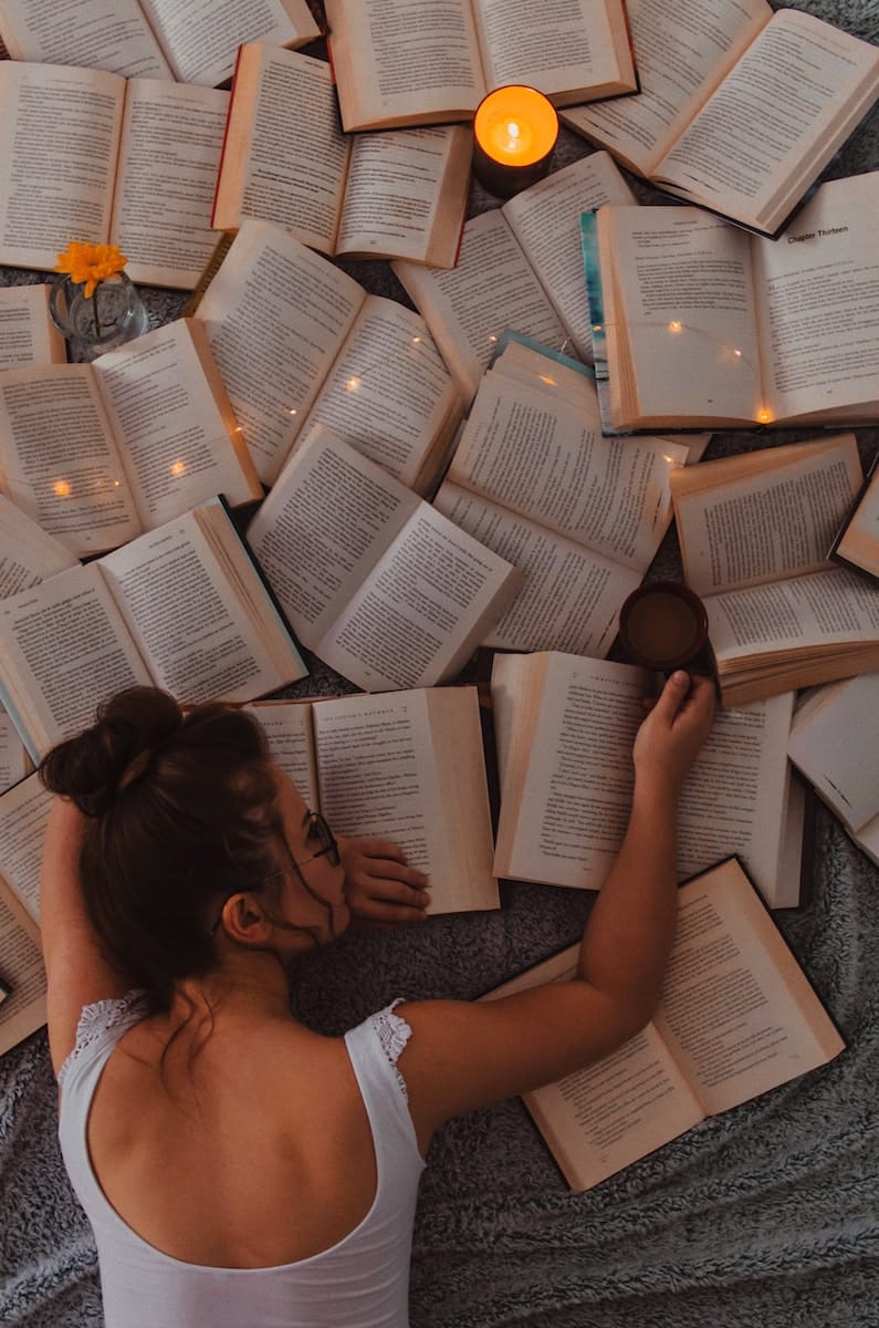 image showing a woman reading a lot of books